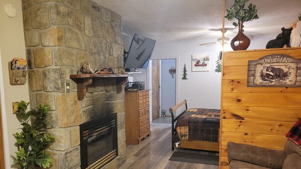 A cozy living room with a stone fireplace, wooden furniture, and a bear-themed decor.