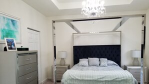 A bedroom with a four-poster bed, a chandelier, a desk with a lamp, and a filing cabinet. - Comfort, Serenity, Relaxation Vacation Home located in Homestead, Florida. (Homestead)