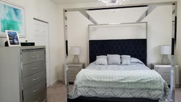 A bedroom with a four-poster bed, a chandelier, a desk with a lamp, and a filing cabinet.