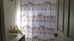 A bathroom with a toilet, a sink with toiletries, and a shower curtain with elephant patterns. - Comfort, Serenity, Relaxation Vacation Home located in Homestead, Florida. (Homestead)
