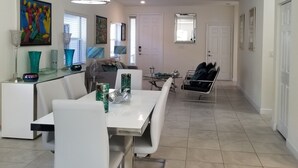 A modern dining area with a white table, chairs, and a chandelier. There is a sofa and a coffee table in the background. - Comfort, Serenity, Relaxation Vacation Home located in Homestead, Florida. (Homestead)