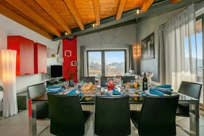 A dining area with a table set for four, a window with a view, and a kitchen area with red cabinets.