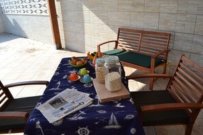 A table with a newspaper, a bowl of fruit, and jars of snacks. - Cosy Apartment near the Beach with Patio & Balcony (san foca)