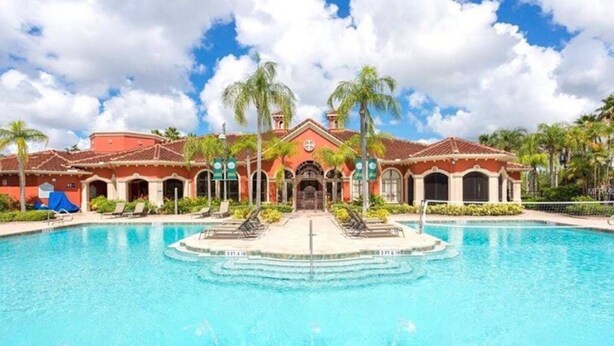 A pool area with a building in the background, palm trees, and a clear sky. - ***  2 bd, 2 bath  Luxury 5 star Italian  Resort, on the hedge of the  Tampa Bay (Clearwater)