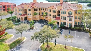 A multi-story hotel with a central courtyard, parking area, and a view of the water and distant buildings. - ***  2 bd, 2 bath  Luxury 5 star Italian  Resort, on the hedge of the  Tampa Bay (Clearwater)