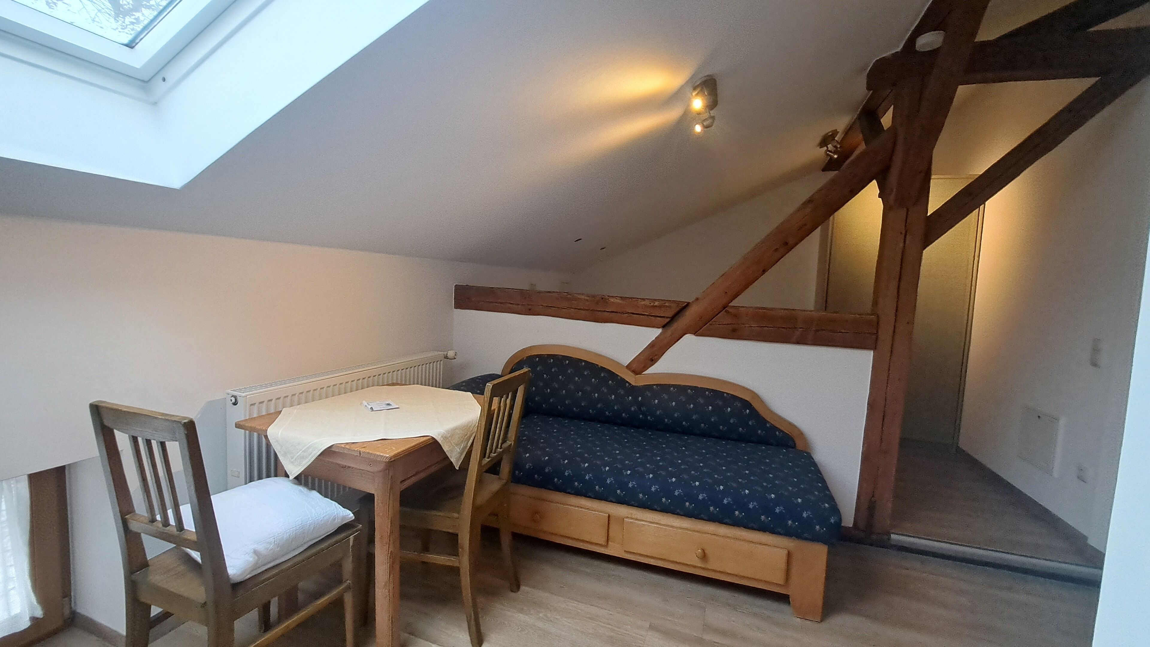 Quarto estilo loft com cama, uma mesinha, uma cadeira e um domo.