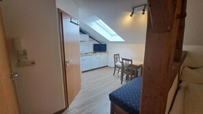 A kitchen with a skylight, a dining area with a table and chairs, and a door leading to another room. - Apartment room no. 9 (Neuötting)