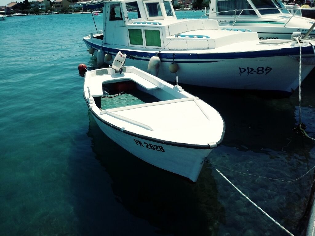 Ein kleines, weißes Boot mit der Kennnummer PR 2628 liegt in einer Marina festgemacht.