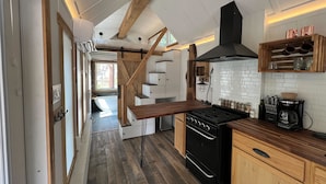 A modern kitchen with wooden beams, a black stove, and a white tiled backsplash. - The Woolly Bugger Inn (Drake)