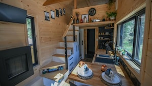 A compact wooden cabin interior with a staircase, a kitchen area, and a dining space. - The Woolly Bugger Inn (Drake)