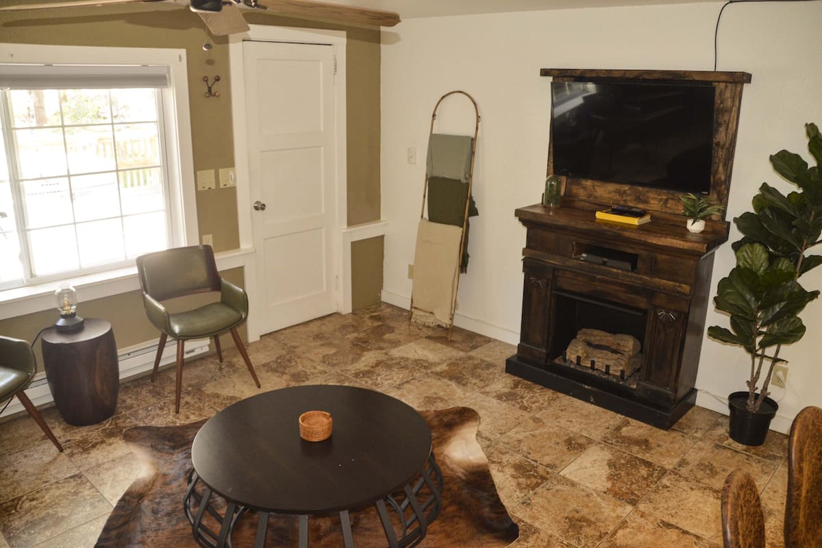A living room with a fireplace, a television, and a large window.
