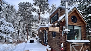 A snowshoe hare cabin with a wooden exterior, a glass door, and a sign indicating its name and species. - The Woolly Bugger Inn (Drake)