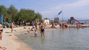 Een druk strand met mensen die zwemmen en spelen in het water.