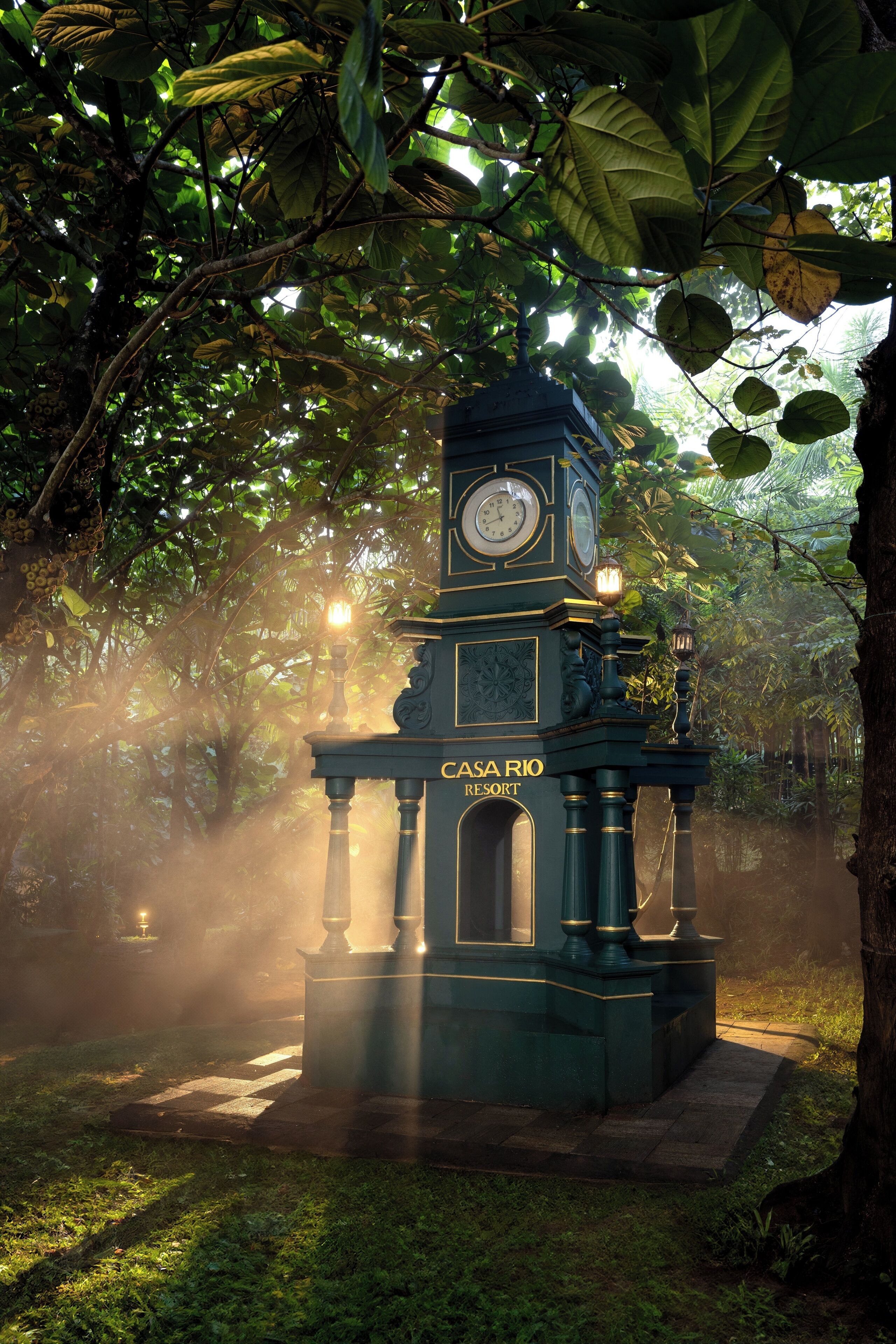 A clock tower with the inscription "CASA RIO" amidst lush greenery.