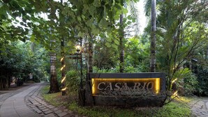 A sign for "CASA RIO" with a brick pathway leading to it, surrounded by lush greenery. - Casa Rio Resort Athirapilly (Chalakudy)