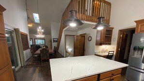 Una cocina con encimera de mármol, armarios de madera y un refrigerador de acero inoxidable.
