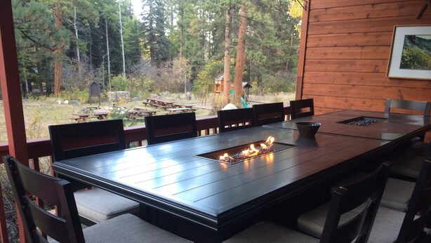 Una mesa de comedor de madera con una chimenea integrada, rodeada de sillas con asientos acolchados.