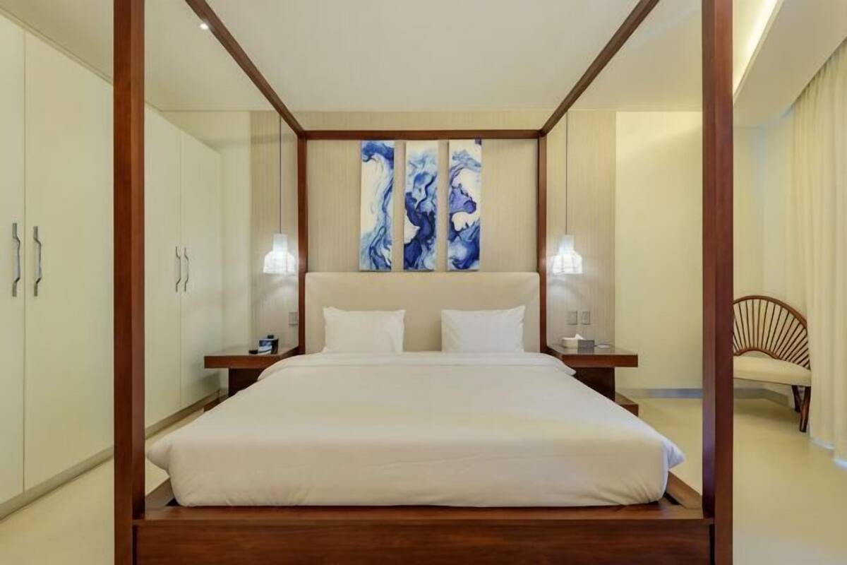 Un dormitorio con una cama grande, cabecera de madera, mesitas de noche y una silla.