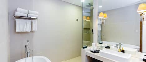 A modern bathroom with a large bathtub, two sinks, and a mirror.