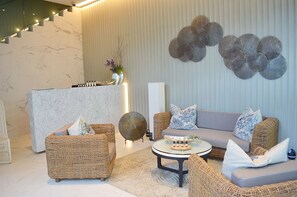 Un'area lounge moderna con mobili in vimini, una reception in marmo e decorazioni murali.