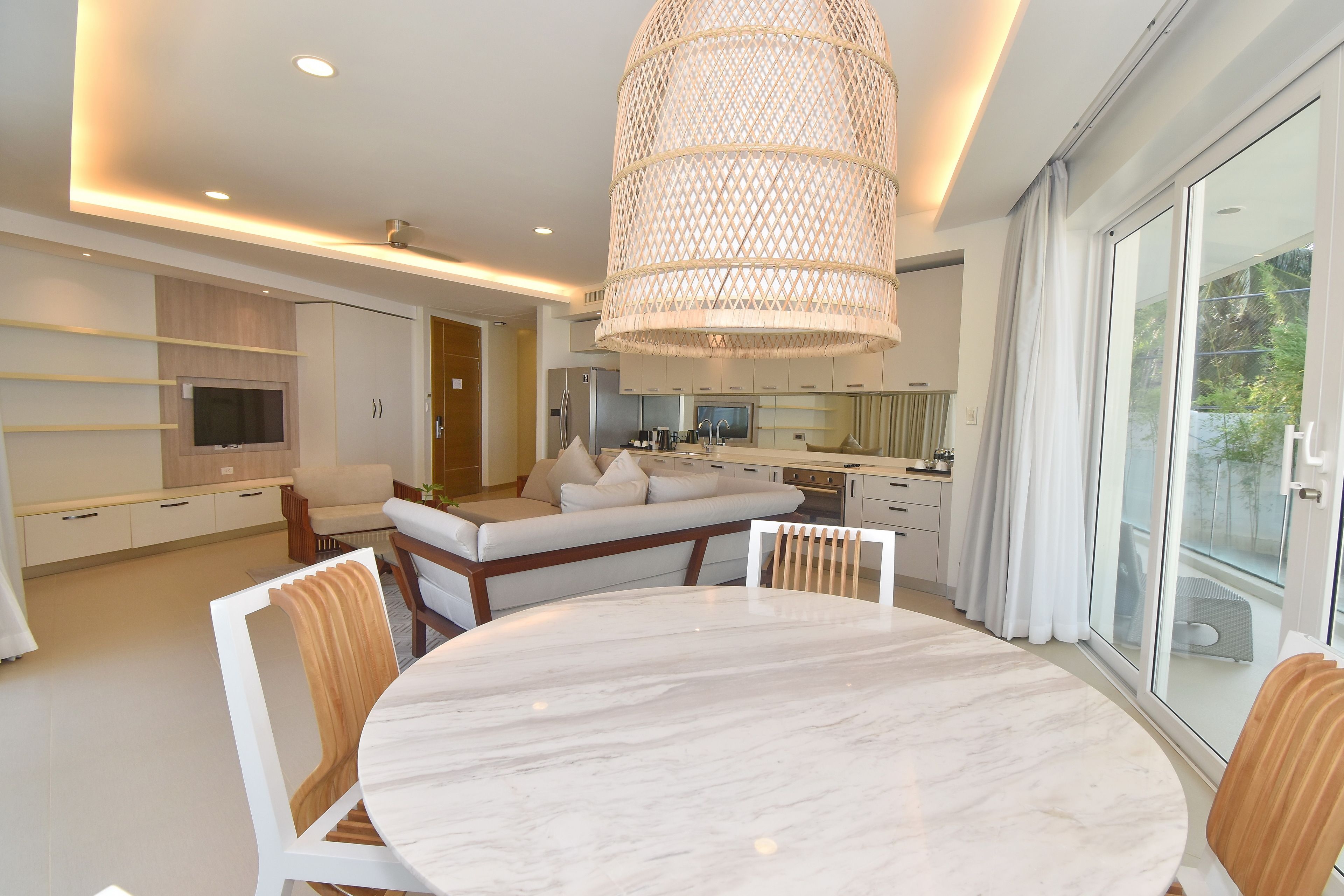 A modern kitchen with a built-in oven, a dining area with a marble table, and a large window with curtains.