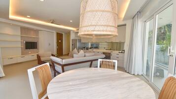 A modern kitchen with a built-in oven, a dining area with a marble table, and a large window with curtains.