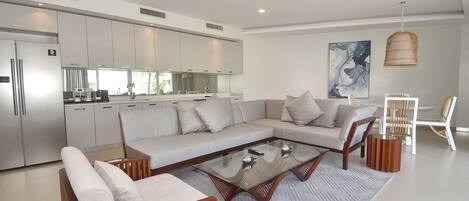A modern living room with a sectional sofa, a glass coffee table, and wooden side tables.
