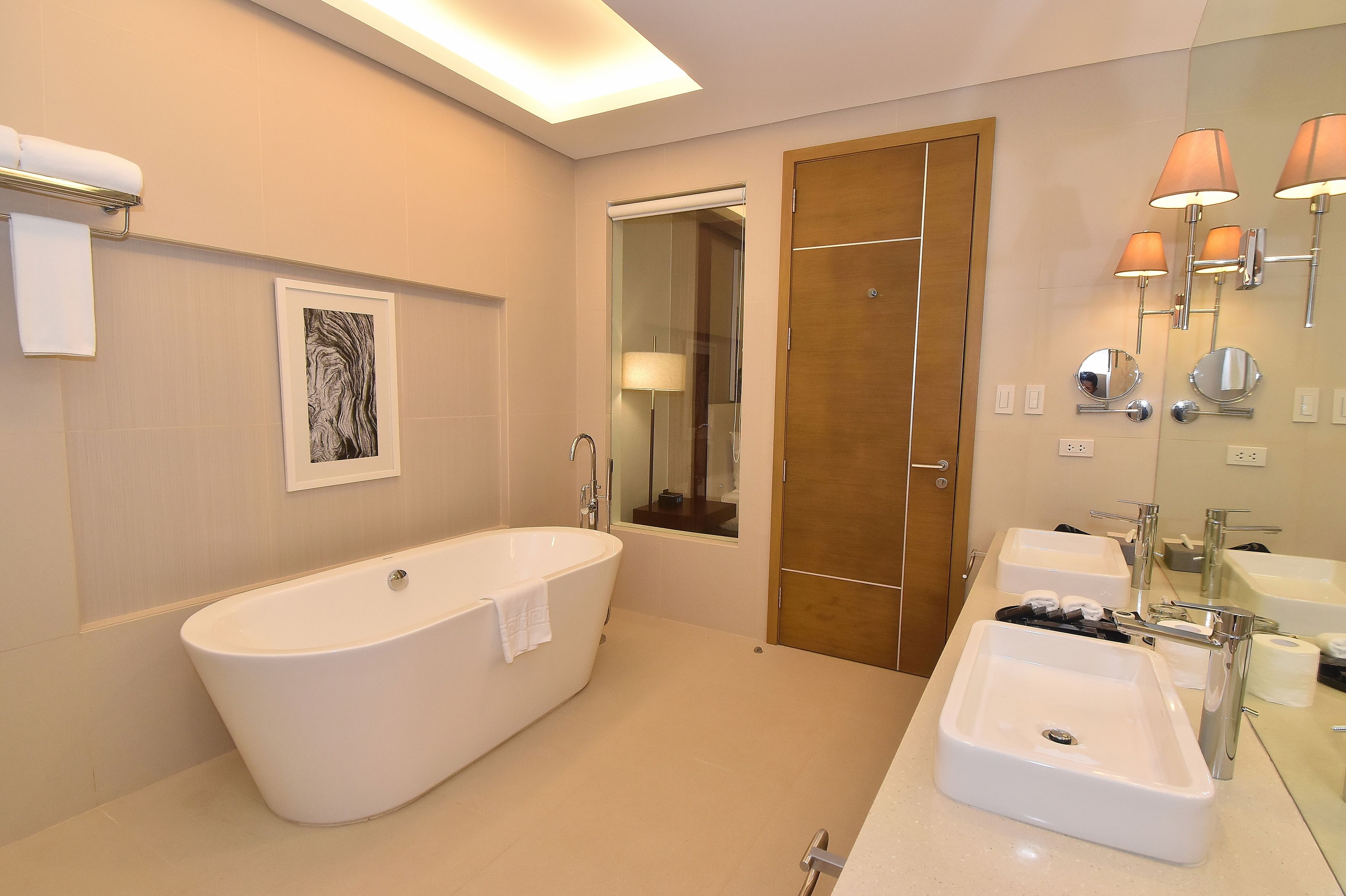 A modern bathroom with a freestanding bathtub, a large mirror, and a vanity with two sinks.