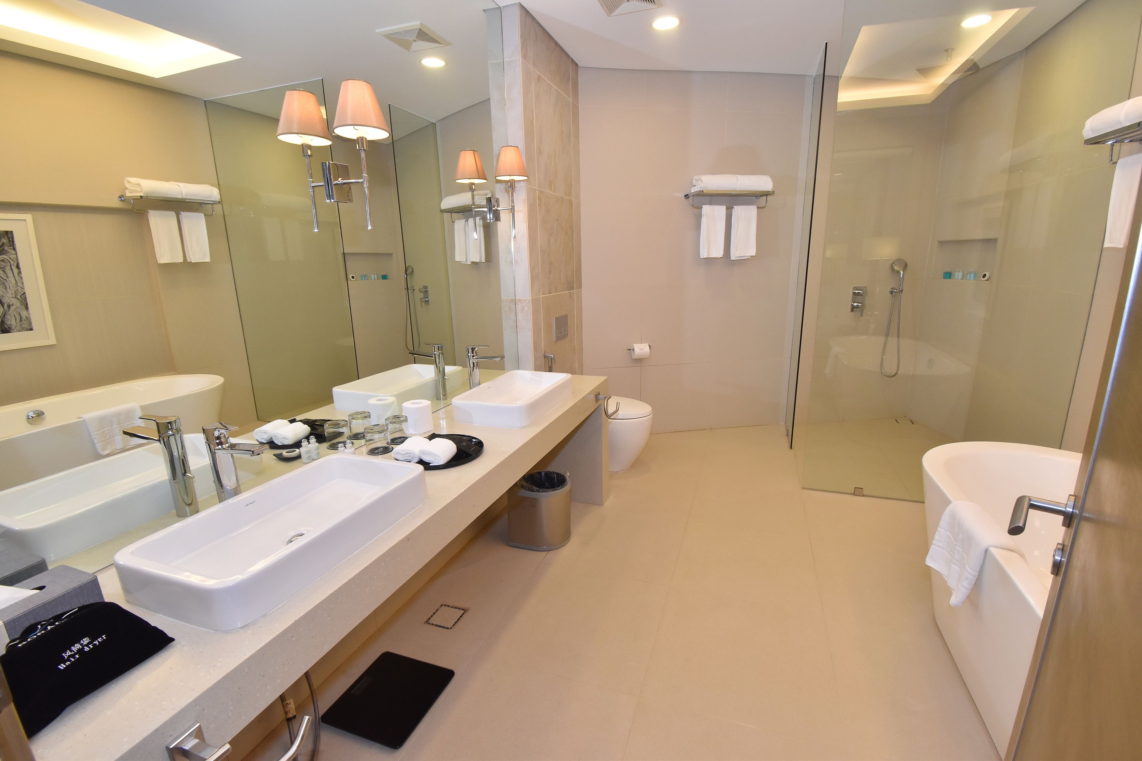 A modern bathroom with two sinks, a glass-enclosed shower, and a large mirror.