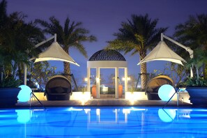 A swimming pool with two large umbrellas, palm trees, and a gazebo in the background. - Mingzuo Hotel Zhongshan (Zhongshan)