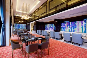 A spacious hotel dining area with multiple tables and chairs, a red patterned carpet, and a large abstract painting on the wall. - Mingzuo Hotel Zhongshan (Zhongshan)