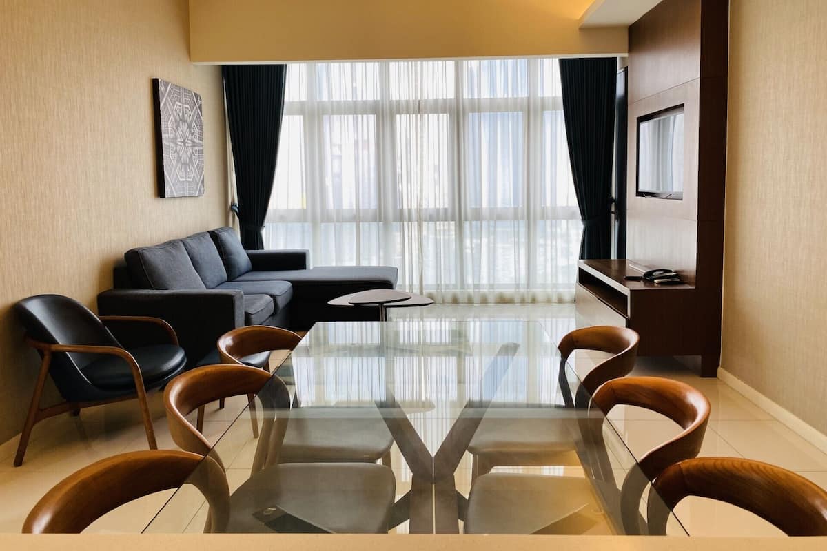 Un salon moderne avec une table basse en verre, des canapés en cuir et un téléviseur à écran plat.
