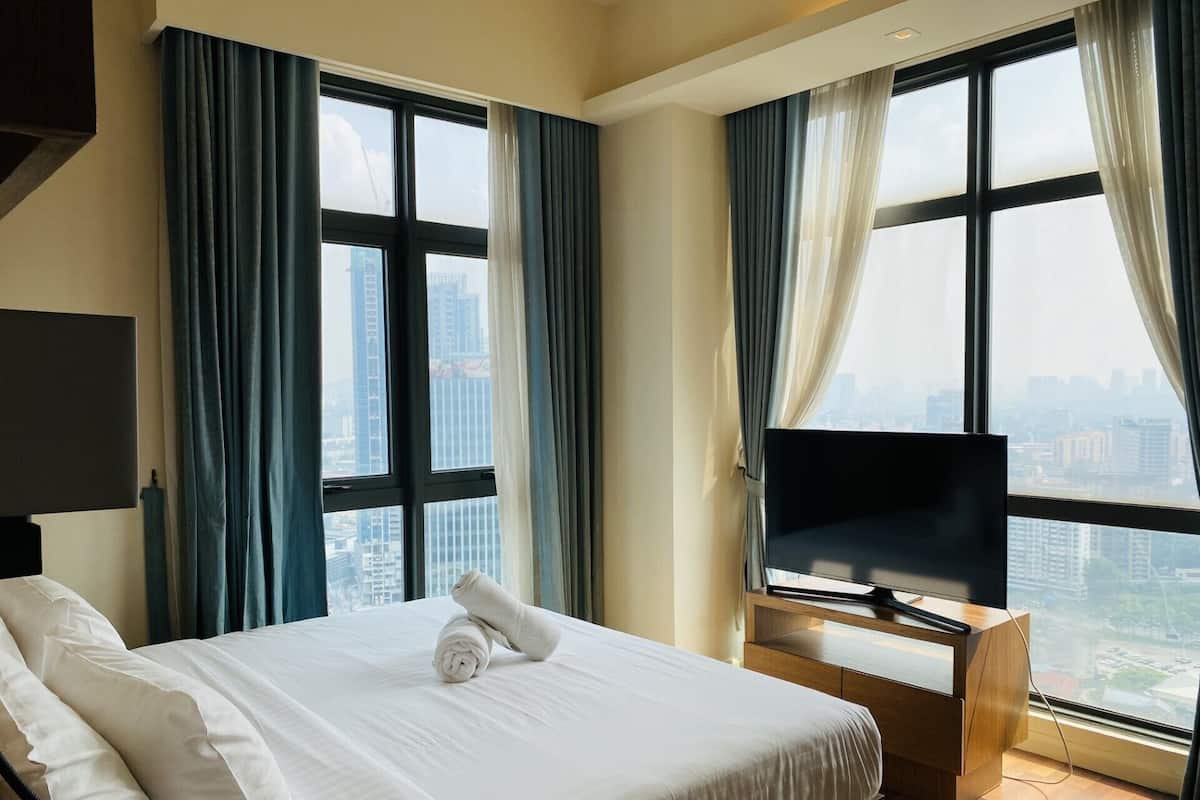 Une chambre d’hôtel avec un grand lit, une télévision et une vue sur la ville.