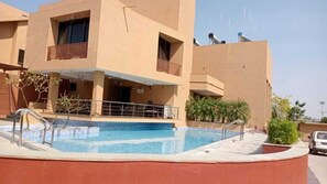 A modern building with a swimming pool, outdoor seating, and satellite dishes. - Pride Resort & Convention Centre (Padadhari)
