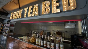 A kitchen area with a sign that reads "BOOK TEA BED" and various kitchen appliances and supplies. - Book Tea Bed Shinjuku-Gyoen (Tokyo)
