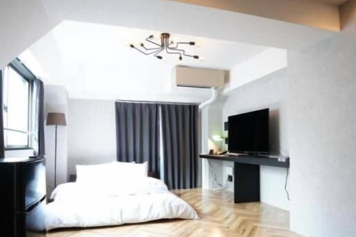 A modern bedroom with a bed, a flat-screen TV, and a ceiling light fixture.