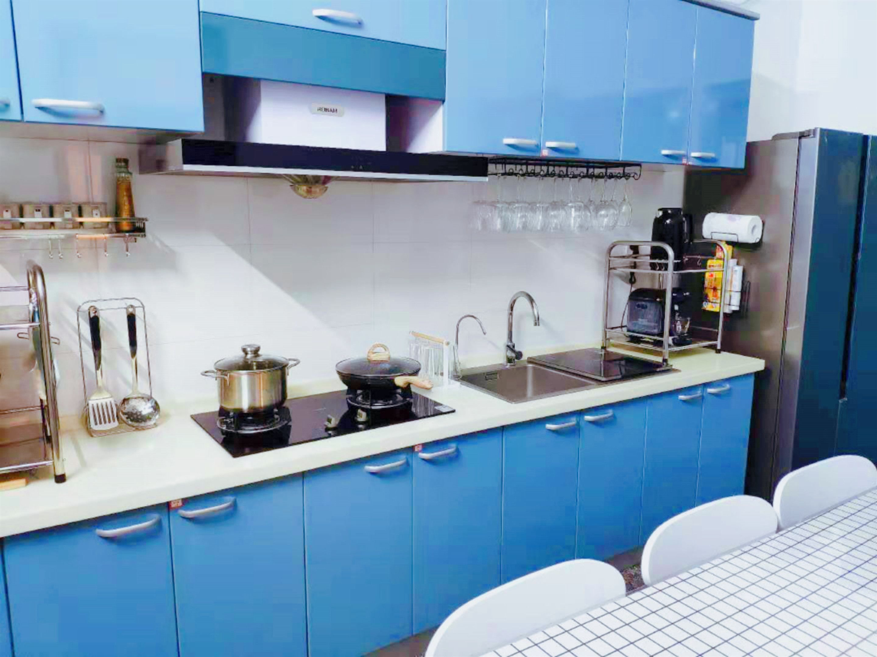 Uma cozinha moderna com armários azuis, uma pia de aço inoxidável e um fogão a gás.