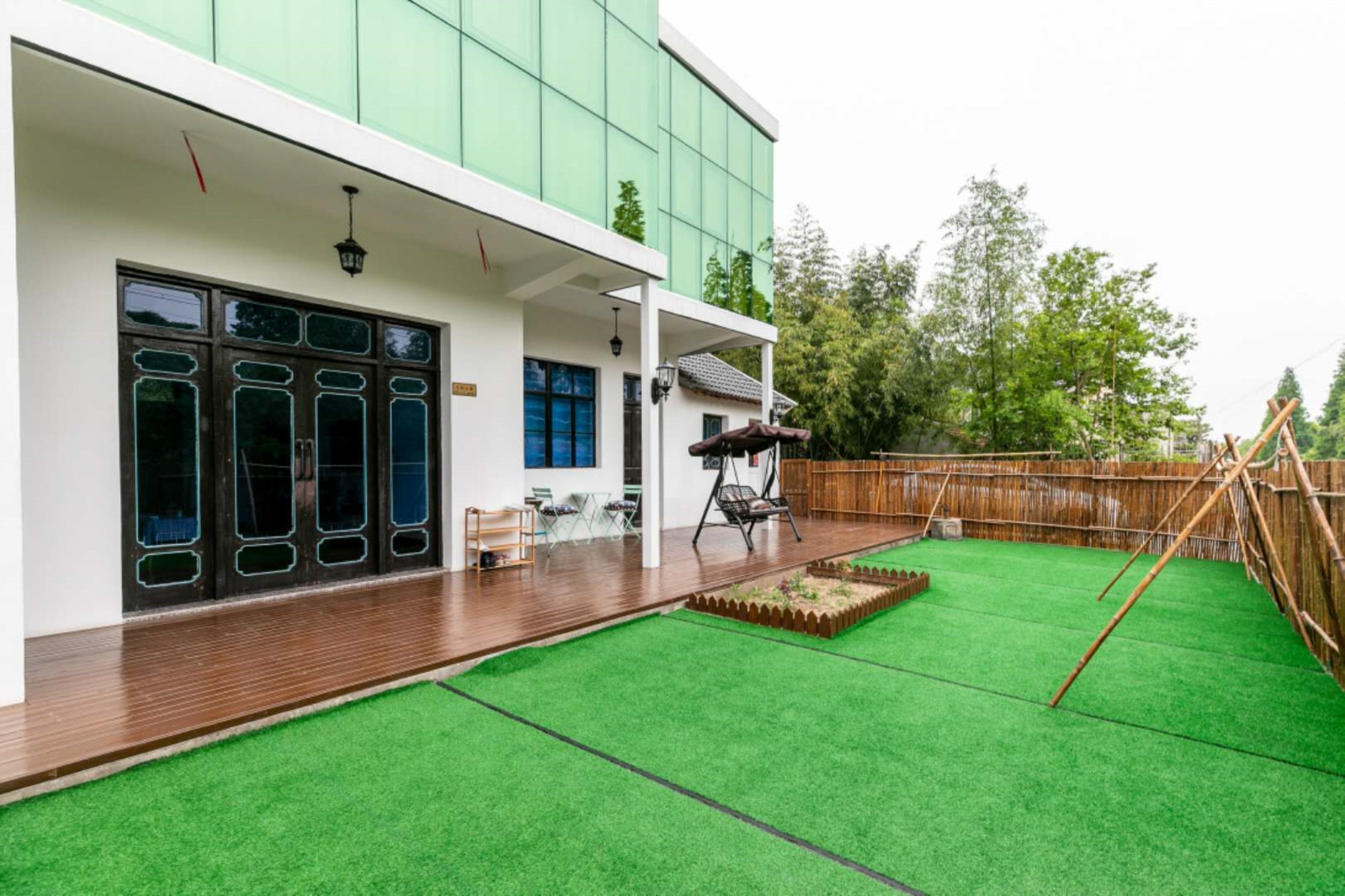 Una casa moderna con un porche cubierto, un césped verde y una terraza de madera.