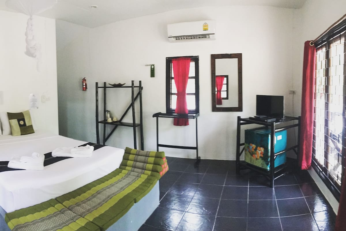 A hotel room with a bed, a TV, a wardrobe, and a window with curtains.