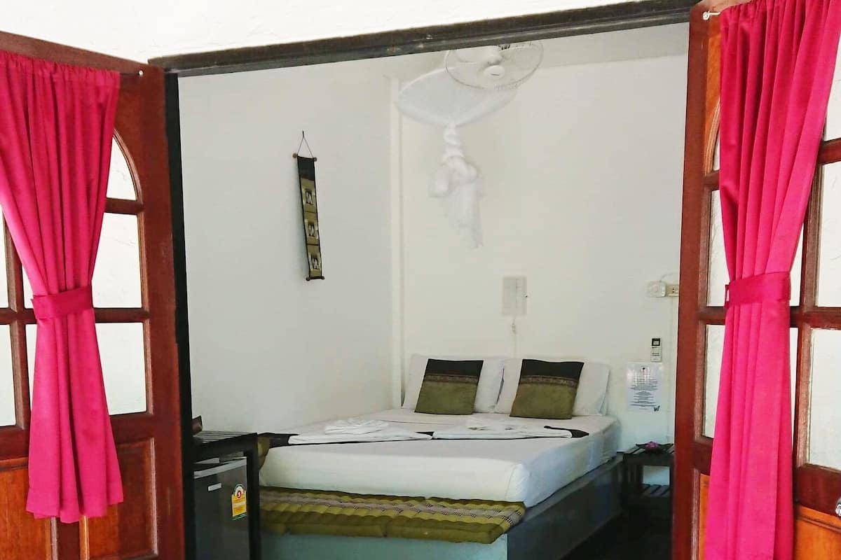 A bedroom with a bed, a nightstand, and a wall-mounted light fixture.