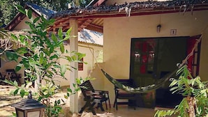 A patio with a hammock, a table, and chairs, surrounded by greenery and a stone pathway. - Papillon Bungalows (Ko Lanta)