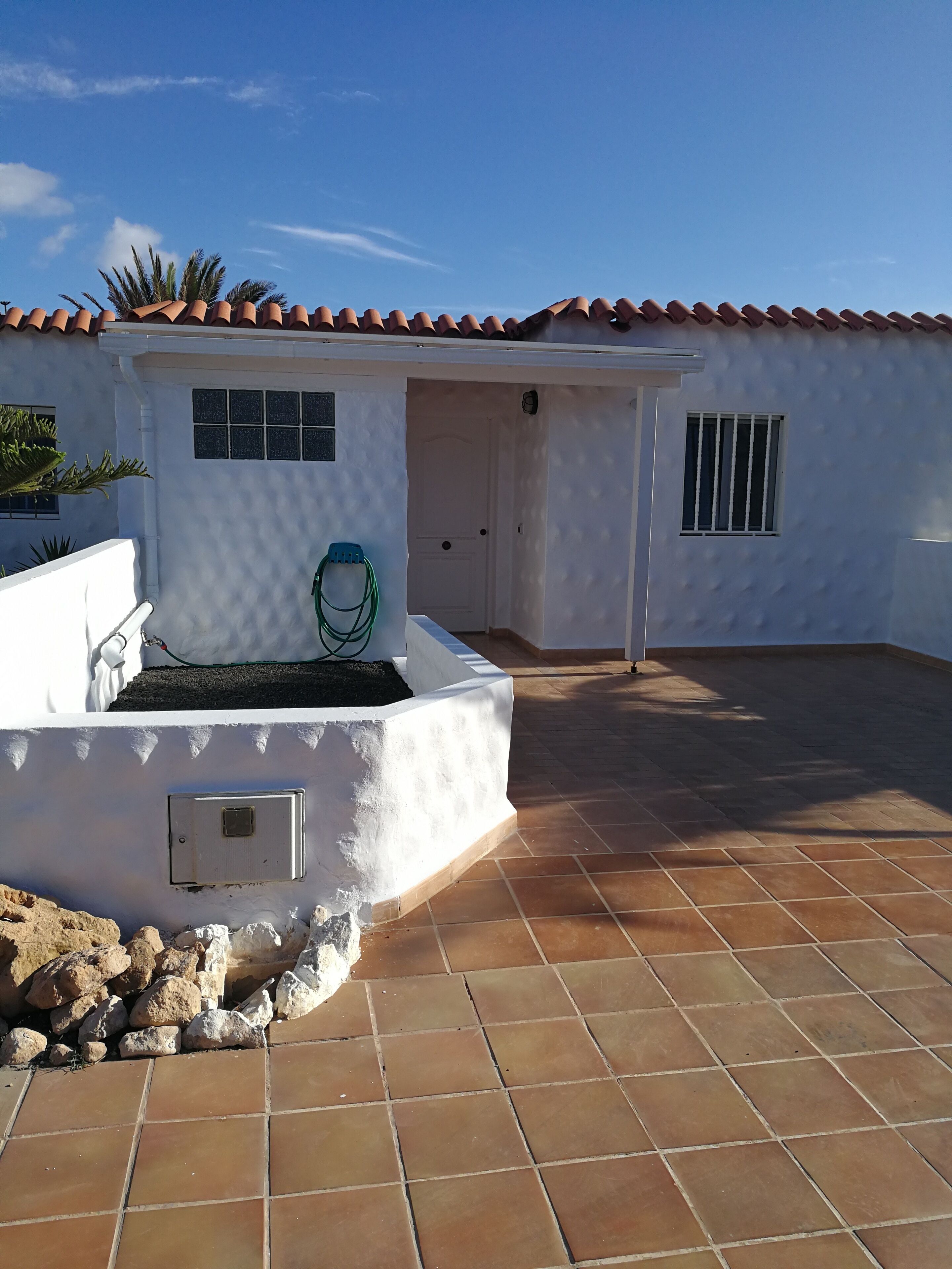 A white building with a tiled roof and a paved patio area.