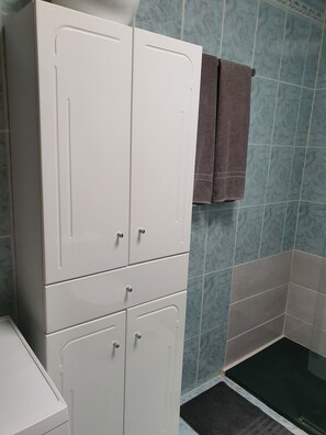 Ein Badezimmer mit weißen Schränken, einem Handtuchhalter und blauen Fliesenwänden.