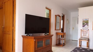 Ett rum med ett träskåp, en tv, en spegel, en stol och en säng med ett täcke som har ett stjärnmönster.