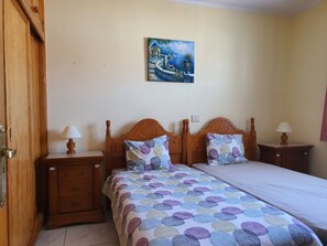 Ein Schlafzimmer mit einem Bett, zwei Nachttischen, einer Holztür und einem Bild an der Wand.
