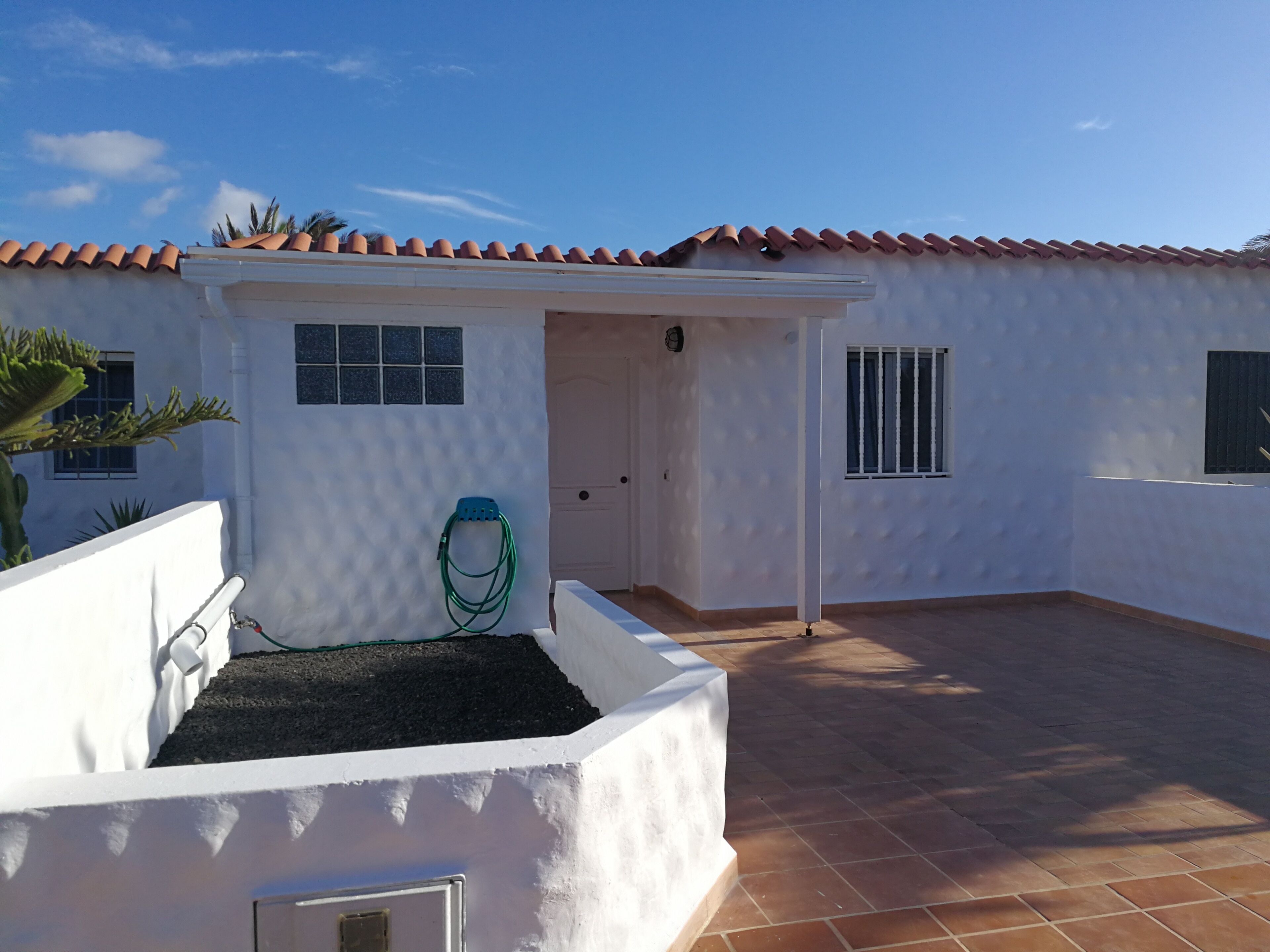 A white building with a tiled roof, a door, and a window.