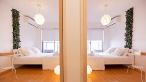 Une vue en miroir d’une chambre à coucher moderne, avec un lit, des tables de chevet et une fenêtre.
