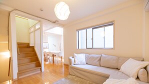 Un salon moderne avec un escalier, un canapé et un coin repas.