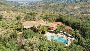 A villa with a swimming pool surrounded by lush greenery and a view of distant hills. - Pet friendly apartment in Laureana Cilento (SA) with swimming pool (Laureana Cilento (SA))