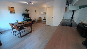 Ett modernt kök med en inbyggd ugn och en matplats med ett träbord och stolar.